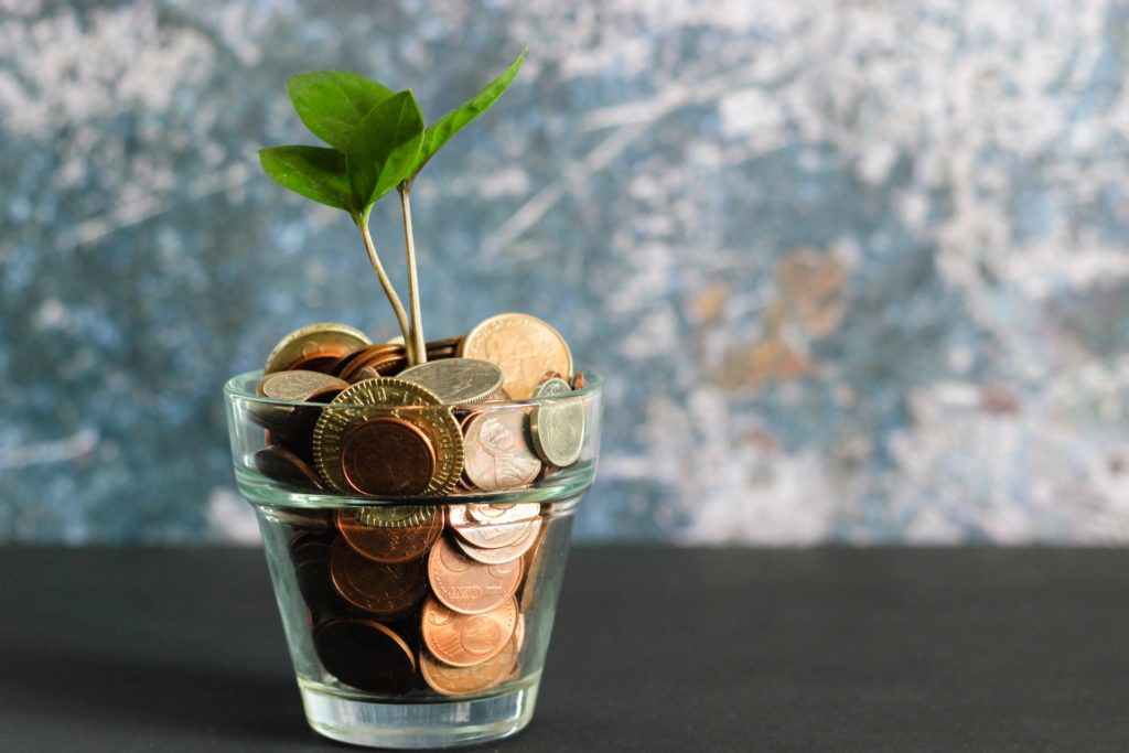 a cup full of coins with a sprout