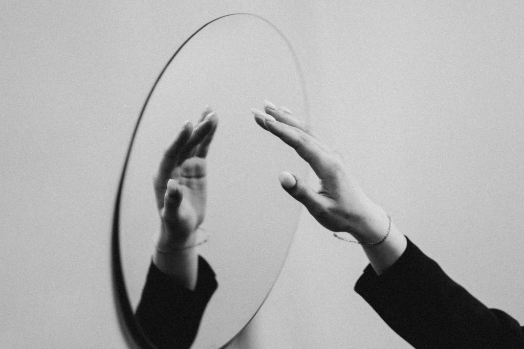 woman reaching toward mirror