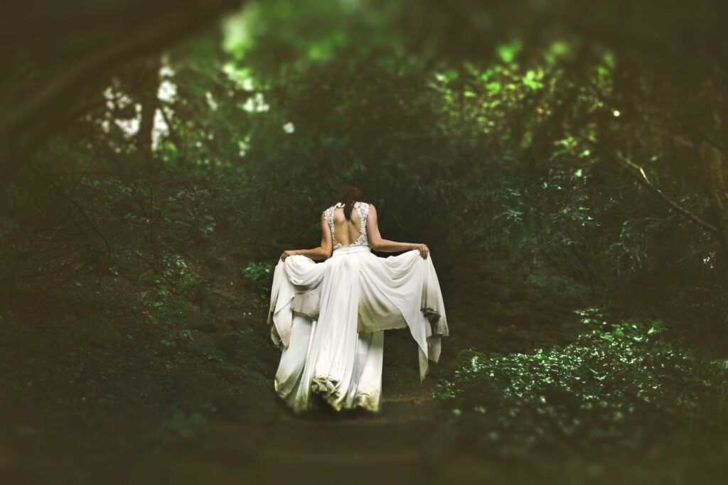 woman in white dress walking in a forest